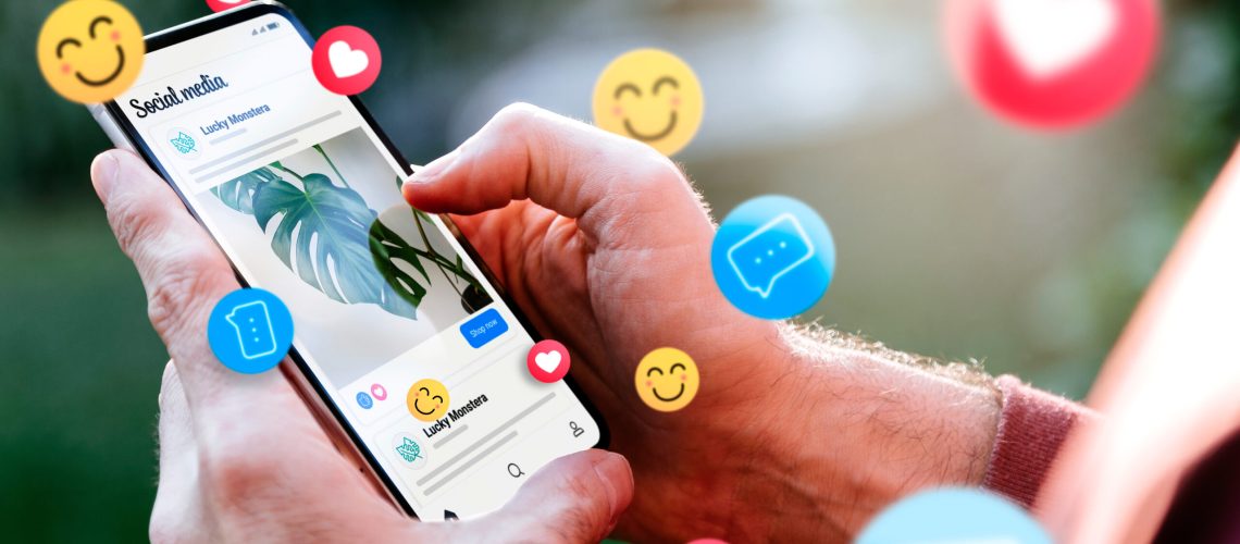 Social media ads on a mobile phone screen with emojis. Man with a smartphone showing an example of a social media ad.